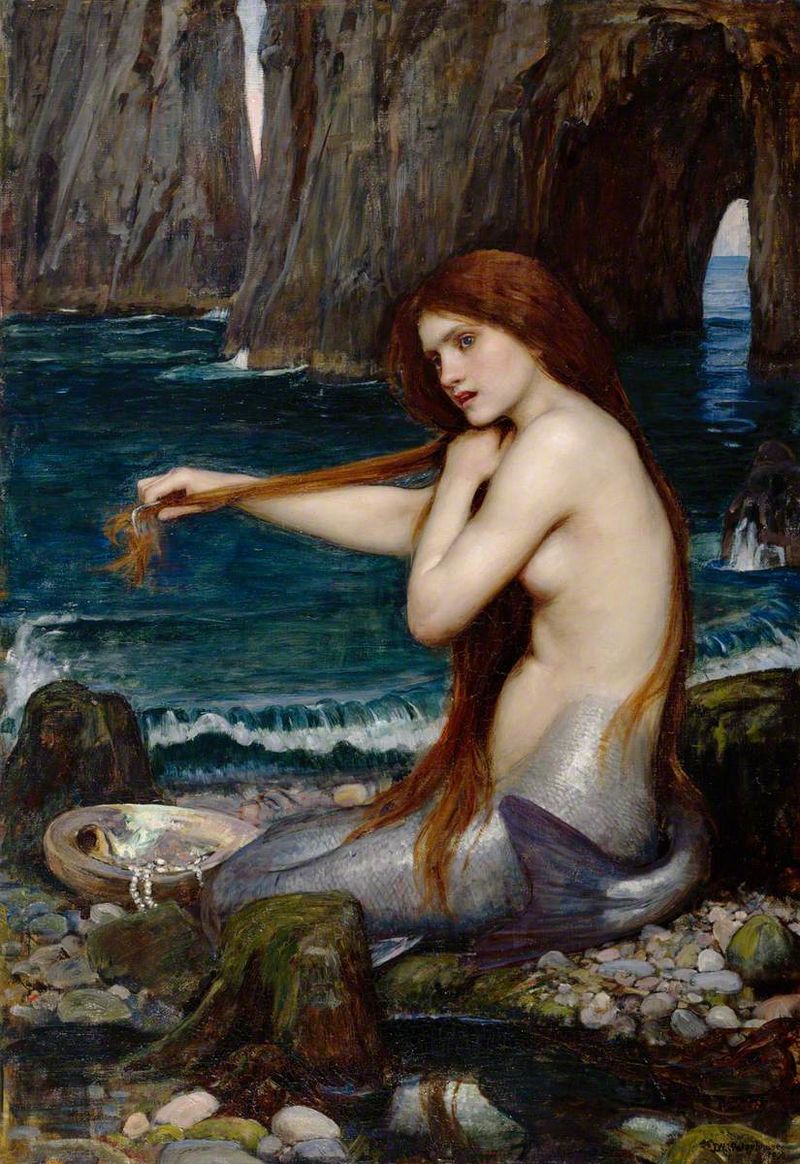 Painting by John William Waterhouse of a mermaid sitting on a rocky shore while she combs her long hair.