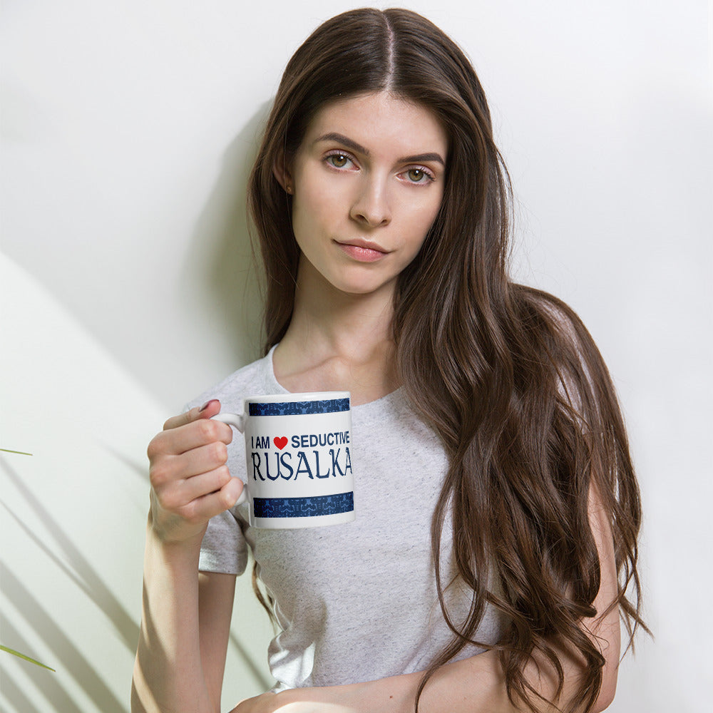 Mockup of a woman holding a white ceramic mug with the saying "I am a seductive rusalka," a Slavic water spirit, often called a mermaid.